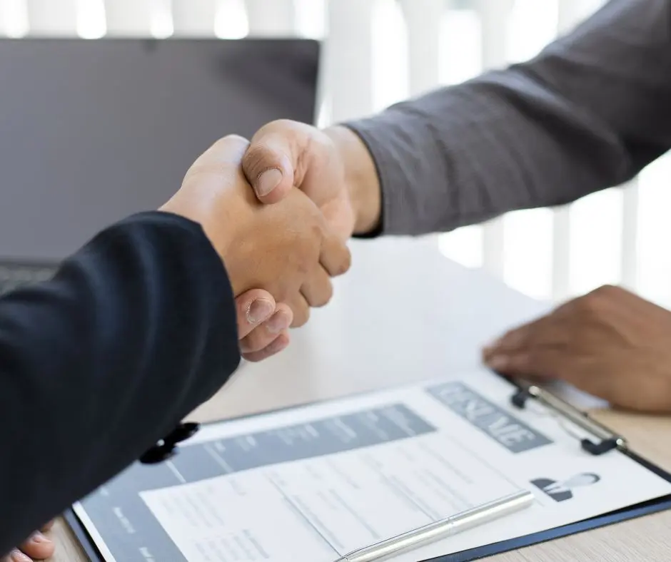 Dos manos estrechando por contrato y despidos